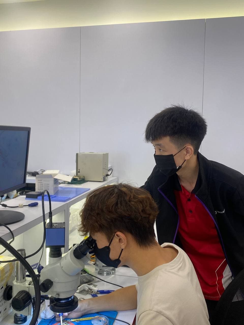 Student at microscope with coach observing